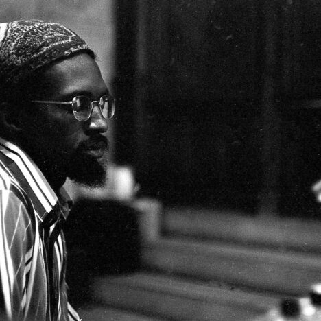 Julius Eastman in a striped shirt and bandana, in profile at a rehearsal